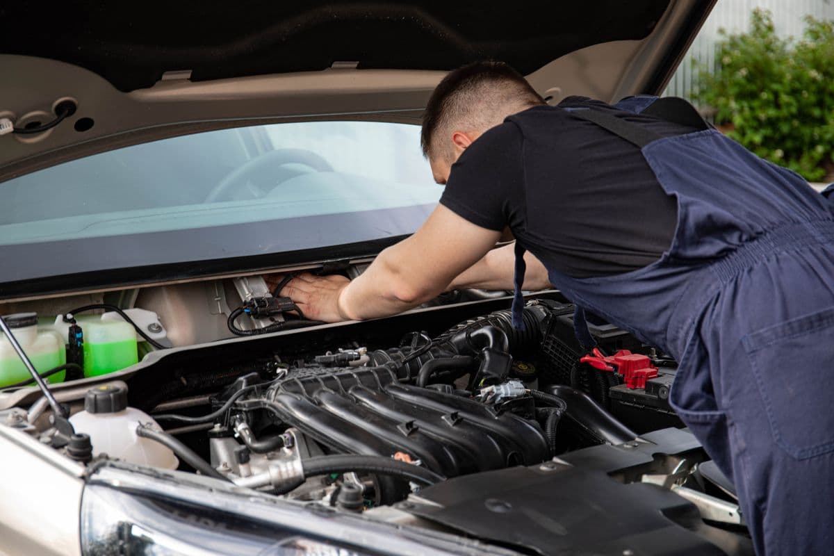 A technician checking an engine under an open hood, illustrating the oil change service.