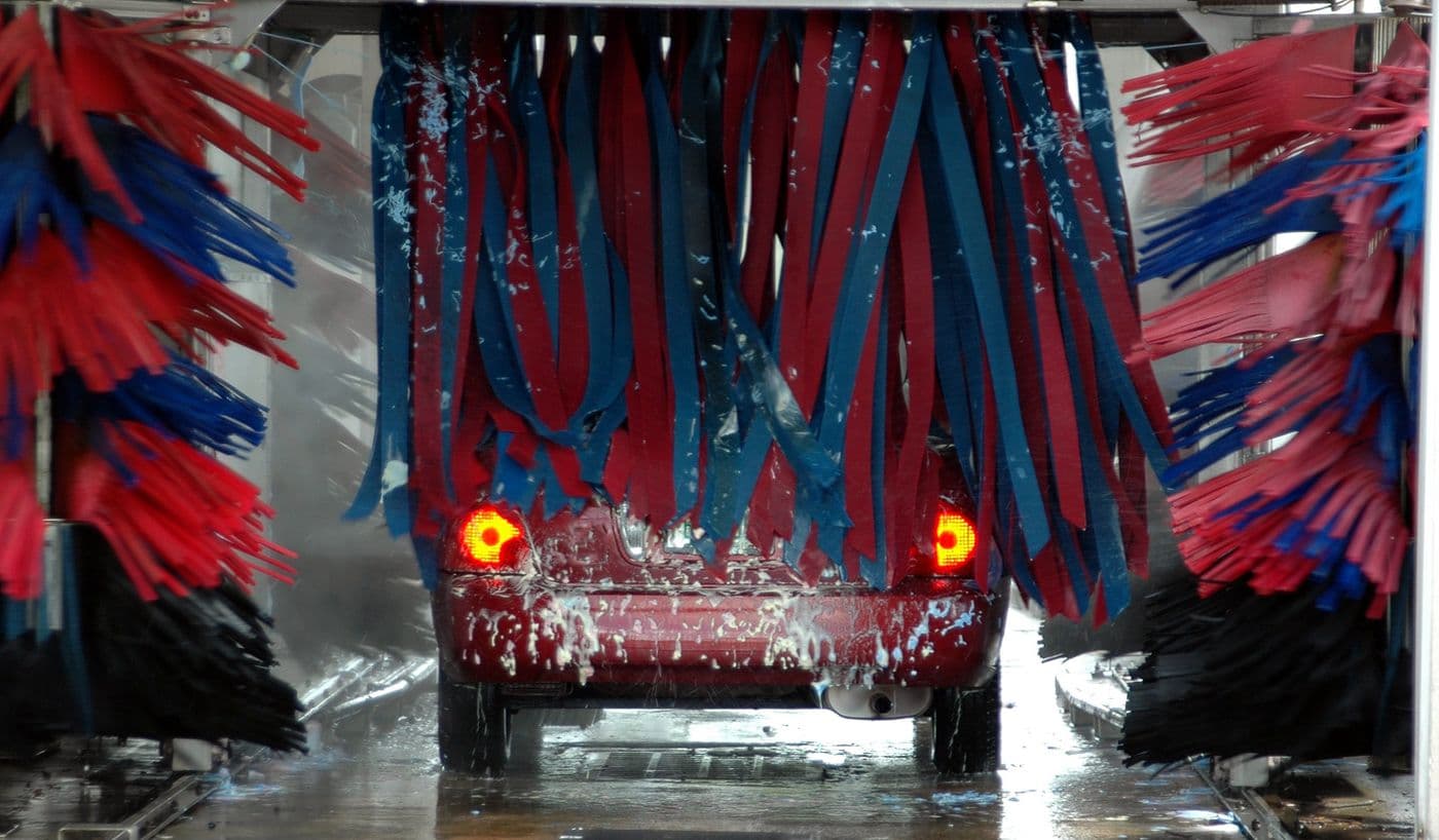 A car moving through automatic brush wash equipment, illustrating the wash services offered.